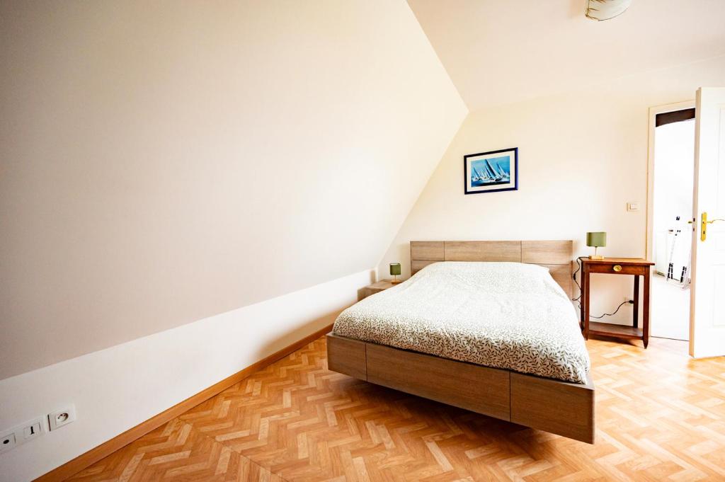 een slaapkamer met een bed en een houten vloer bij L'échappée belle in Fontenay