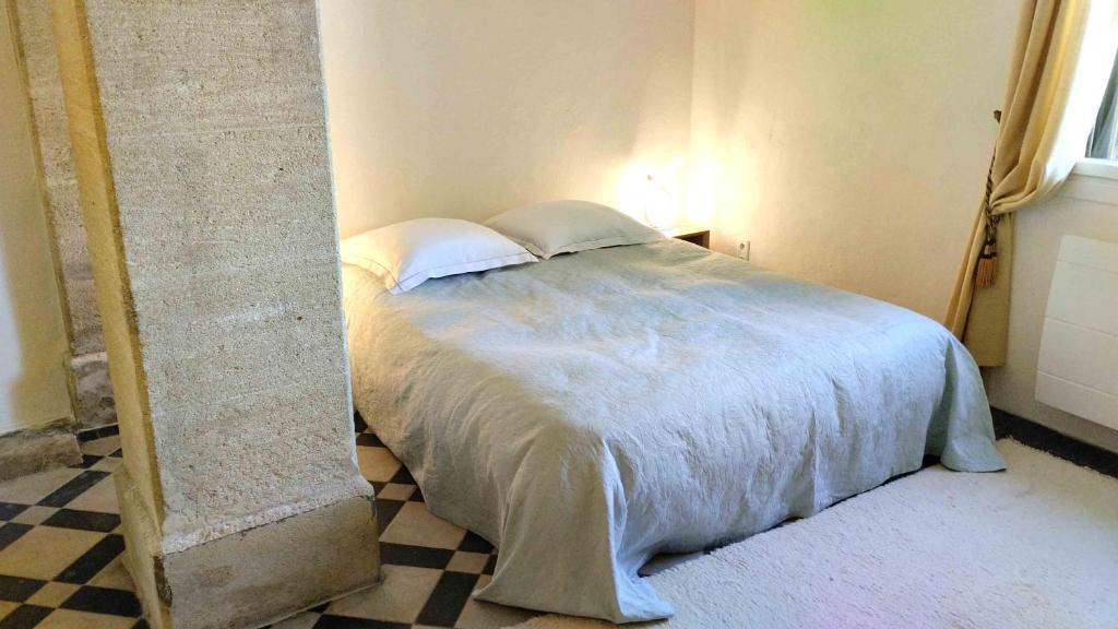 uma cama com duas almofadas num canto de um quarto em Au Fil de l'Eau 30 em Remoulins