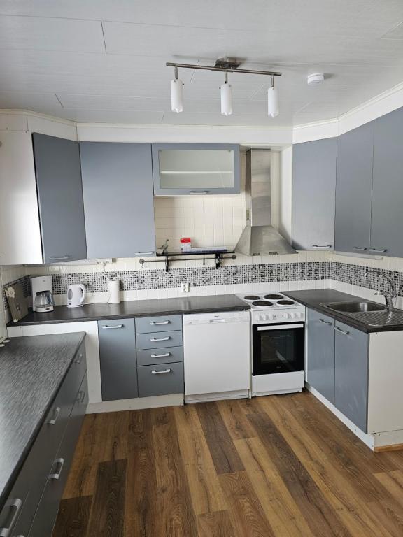 a large kitchen with white appliances and wooden floors at Majoitus Kulma in Ilomantsi