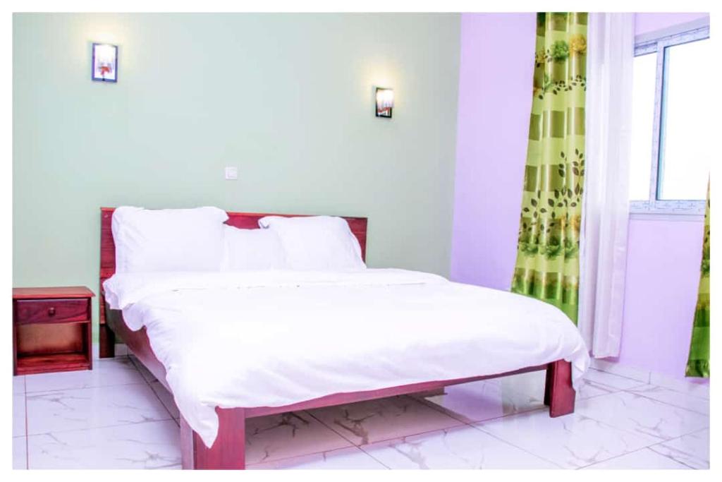 1 dormitorio con 1 cama con sábanas blancas y ventana en Résidences K and D CAMOCO, en Bafoussam