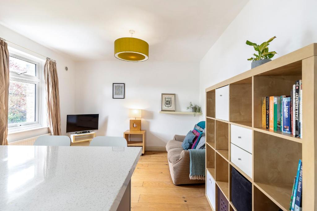 ein Wohnzimmer mit Bücherregal und Sofa in der Unterkunft A Tranquil One-Bedroom Flat near Brockwell Park in London