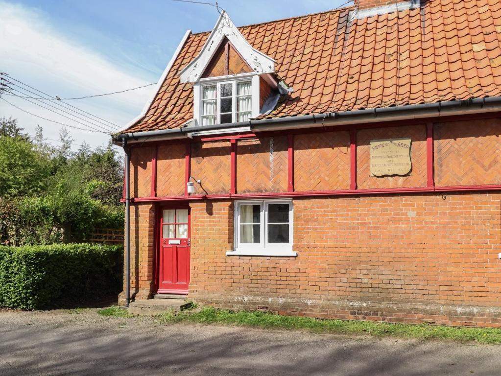 una casa de ladrillo rojo con puerta roja en 2 The Almshouses, en Saxmundham