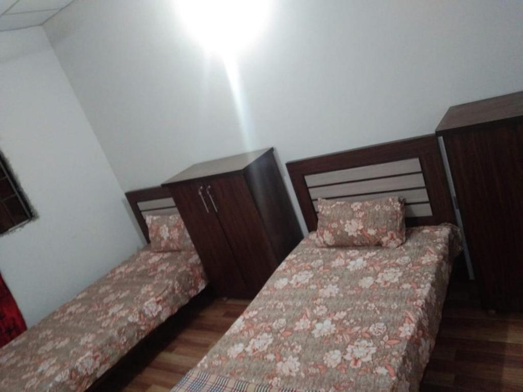 2 bedden in een kleine kamer met een nachtrok bij H.Y Boys Hostel & Rooms for Rent in Karachi