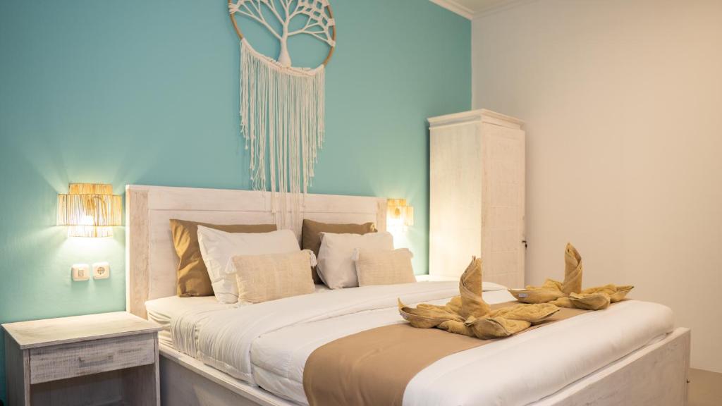 une chambre avec un grand lit blanc avec des plumes dessus dans l'établissement The White Bay Lombok, à Kuta Lombok
