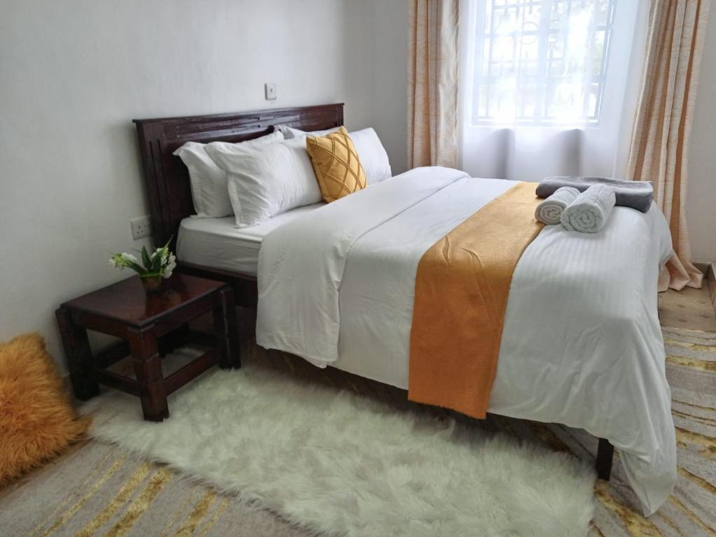 Kai Suites Kitale في كيتالي: غرفة نوم بسرير كبير مع سجادة