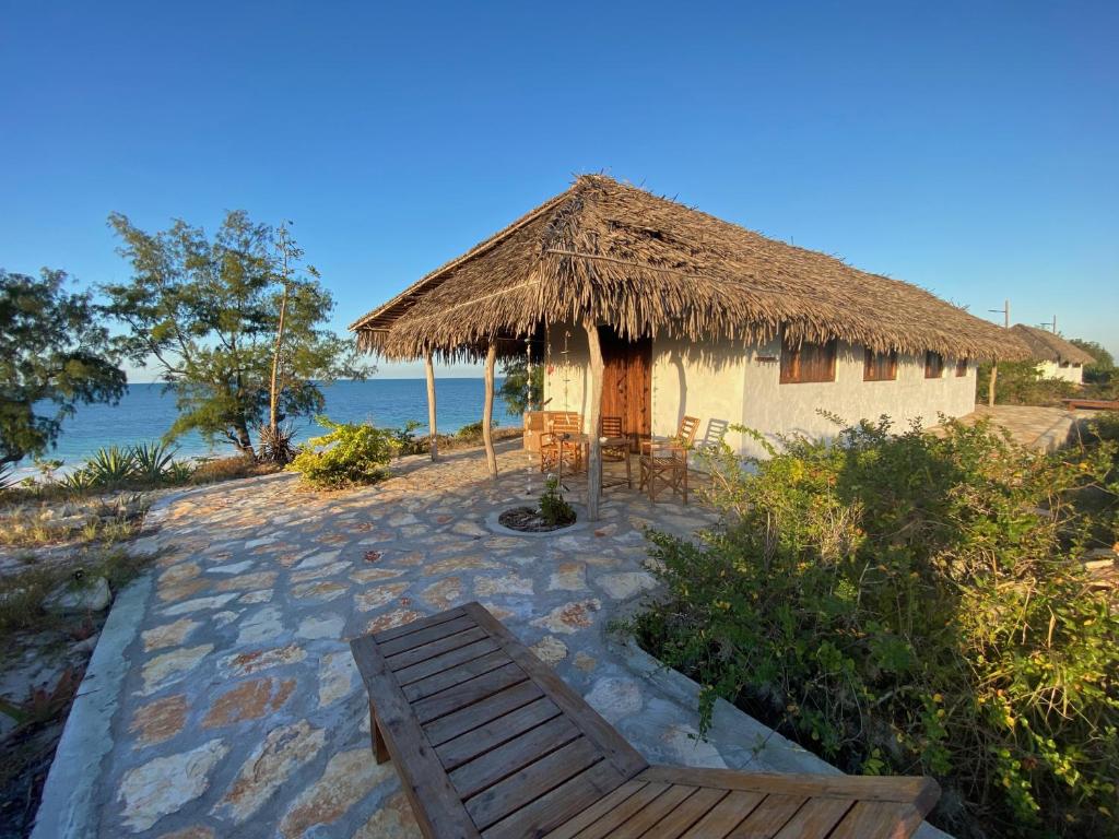 uma pequena cabana com um banco e um telhado de palha em Namahamade Lodge Restaurante & Beach Bar em Mossuril