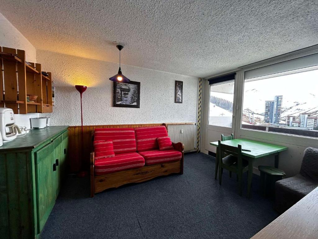 ein Wohnzimmer mit einem roten Sofa und einem Tisch in der Unterkunft Studio Les Menuires, 1 pièce, 2 personnes - FR-1-452-264 in Les Menuires