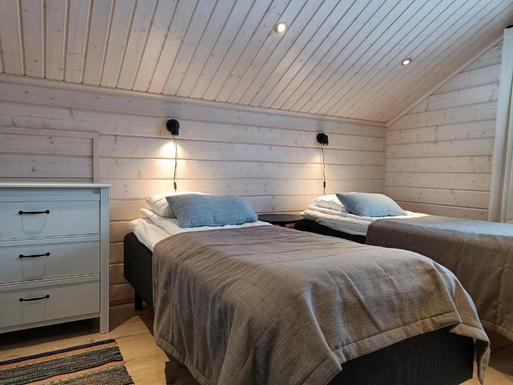 2 Betten in einem Zimmer mit Holzwänden in der Unterkunft Rantatähti Villa in Syöte