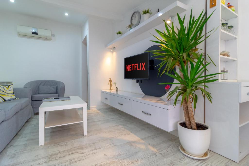 een woonkamer met een tv en een palmboom bij Alex Suites Lara in Antalya