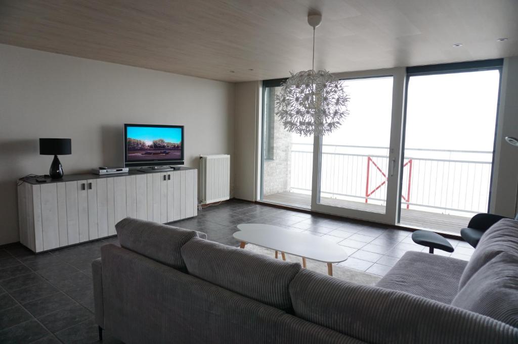 een woonkamer met een bank en een tv bij Kustverhuur, Prachtig appartement met uitzicht op zee, Port Scaldis 09-051 in Breskens