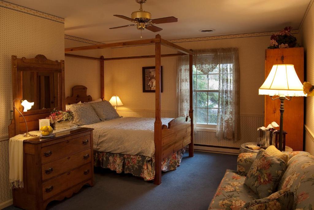 1 dormitorio con cama con dosel y sofá en Eagle Harbor Inn, en Ephraim