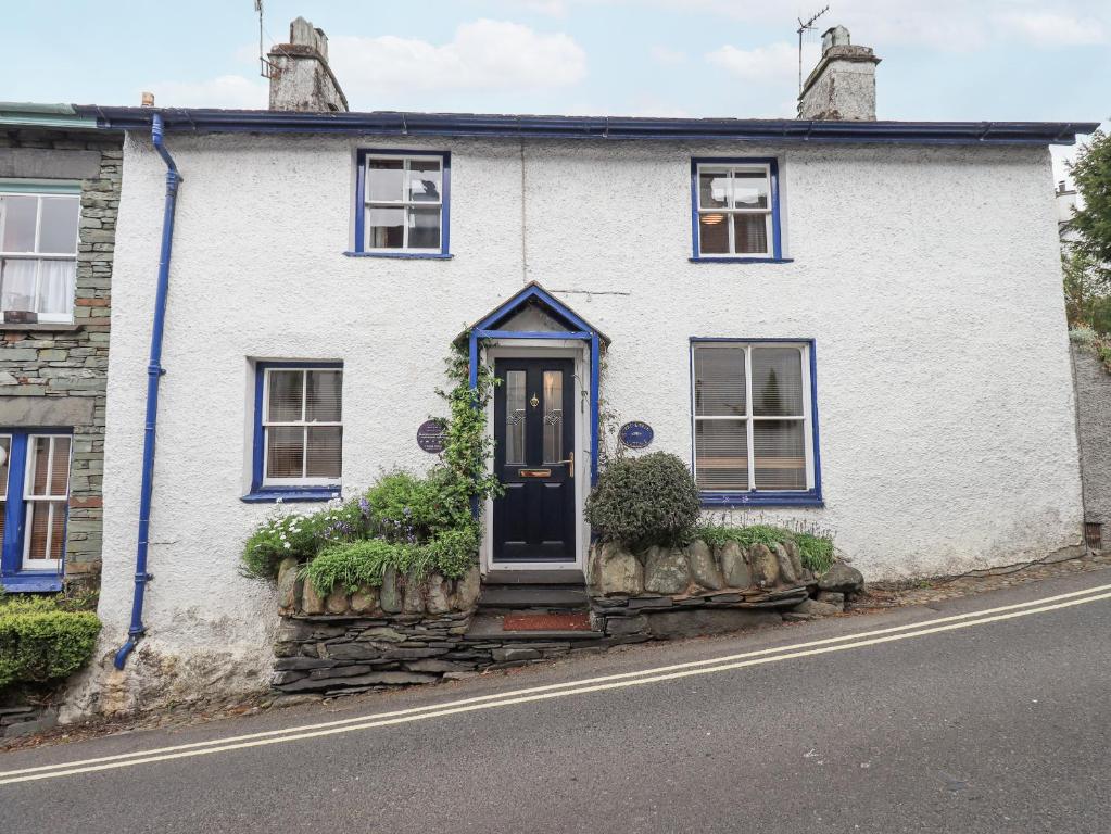 a white house with a blue door on a street at Springwell Cottage in Ambleside