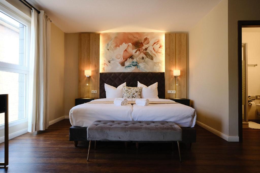 a bedroom with a large bed with a painting on the wall at PARKHOTEL - Rosarium in Uetersen