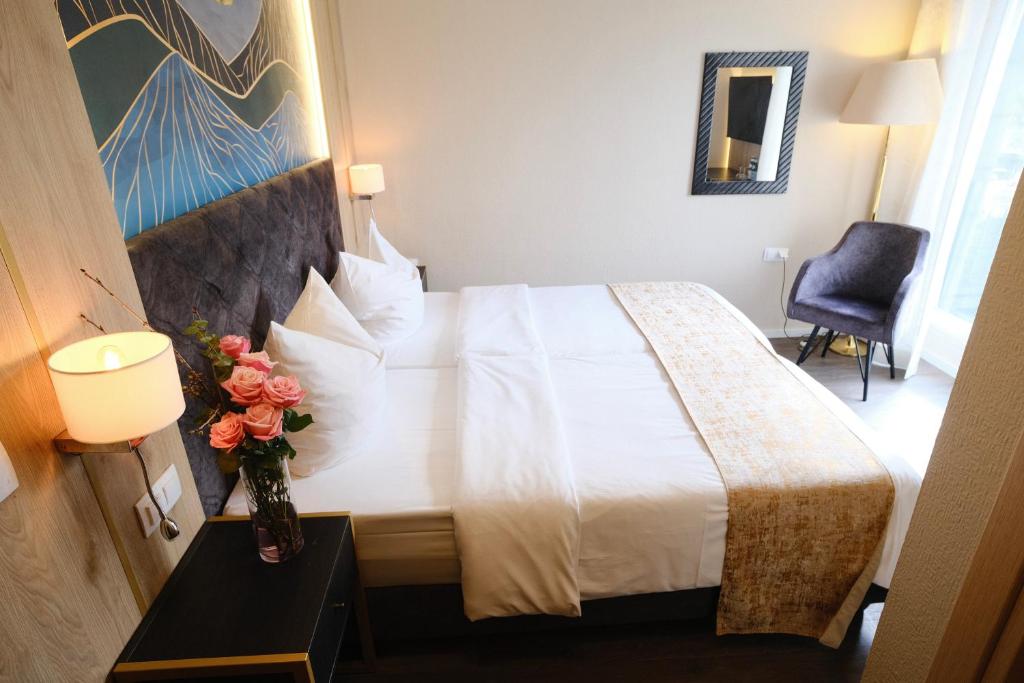 a hotel room with a bed and a vase of flowers at PARKHOTEL - Rosarium in Uetersen