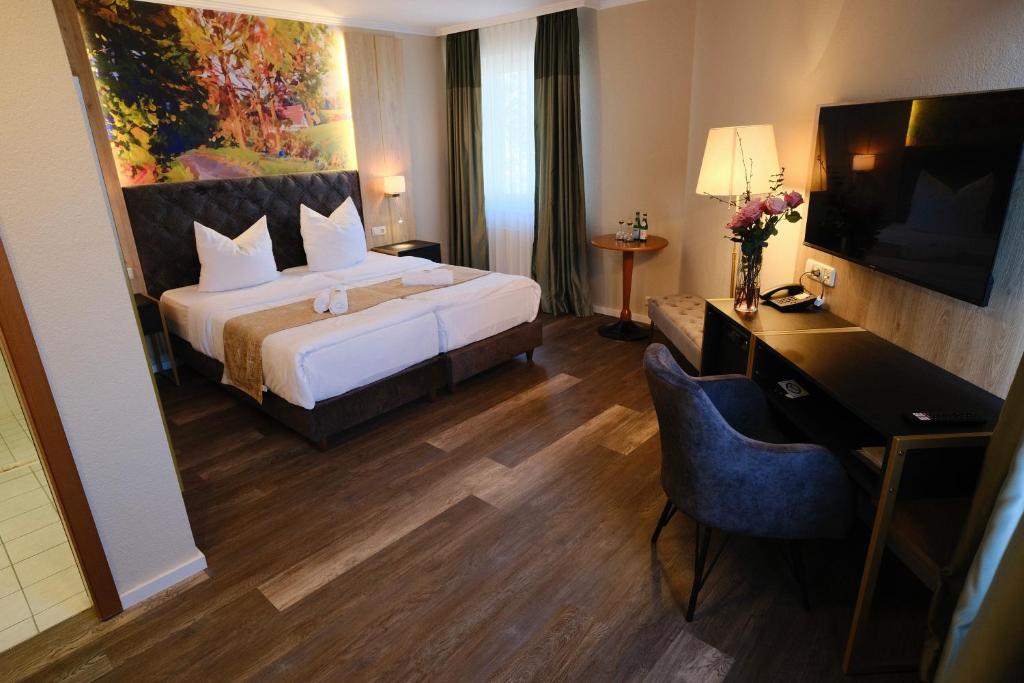 a hotel room with a bed and a desk and a television at PARKHOTEL - Rosarium in Uetersen