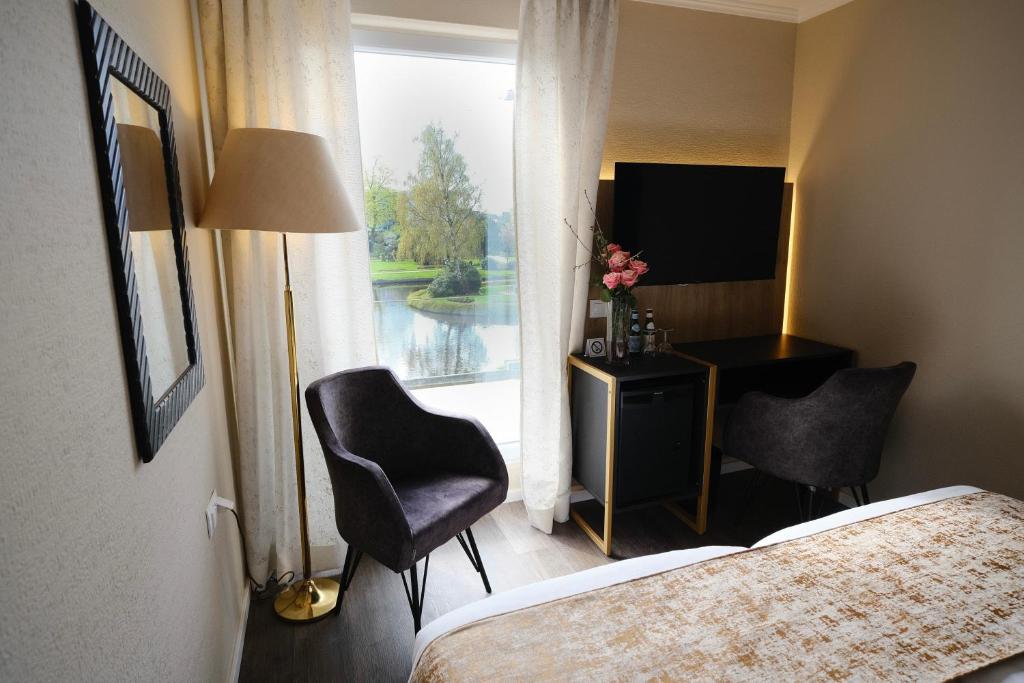 a hotel room with a bed and a desk and a window at PARKHOTEL - Rosarium in Uetersen