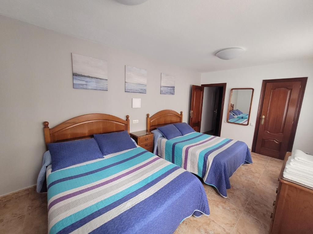 a bedroom with two beds with blue and striped sheets at Hostal San Felix in Gijón