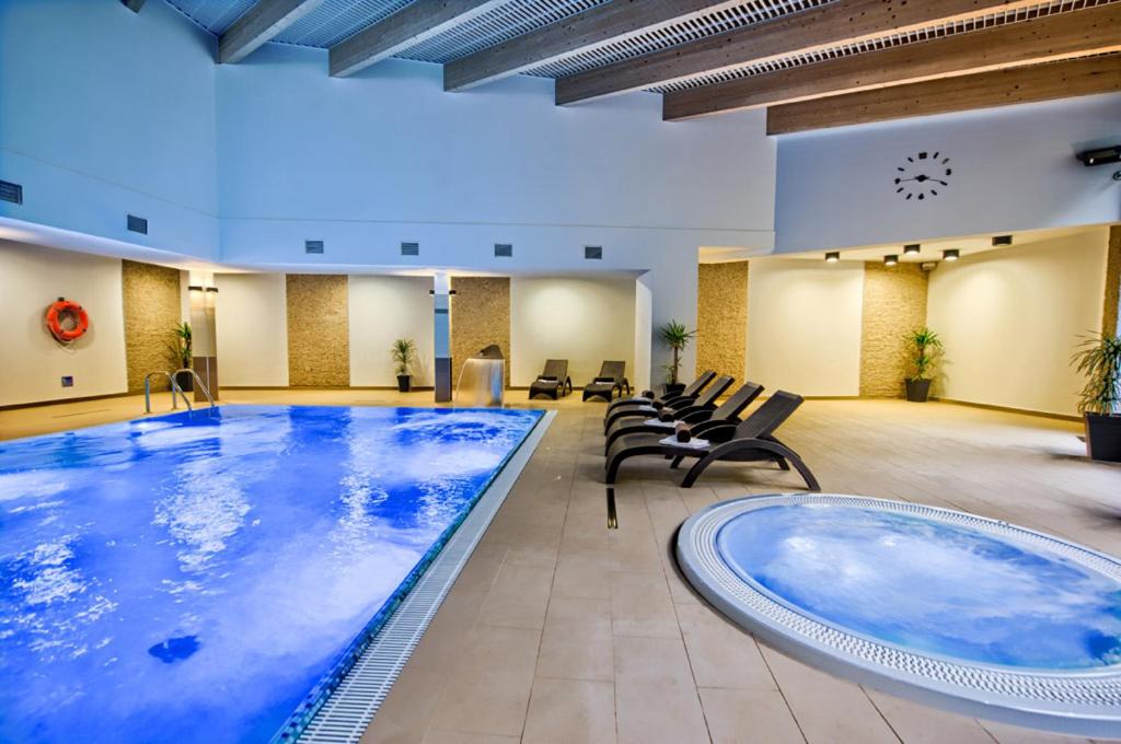 una grande piscina in una grande stanza con sedie di Hotel Zimnik Luksus Natury Spa & Wellness a Szczyrk