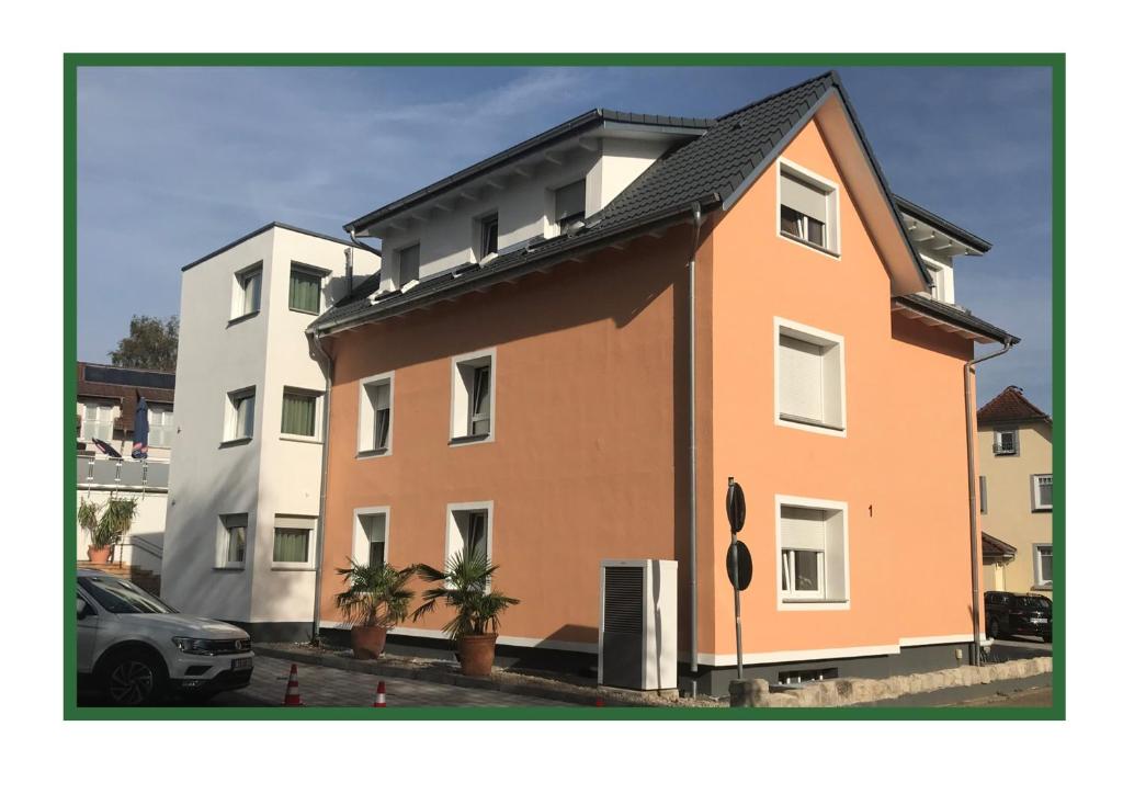 ein großes orangefarbenes Gebäude neben zwei weißen Gebäuden in der Unterkunft Bodensee Sunshine Zimmer & Apts. in Uhldingen-Mühlhofen