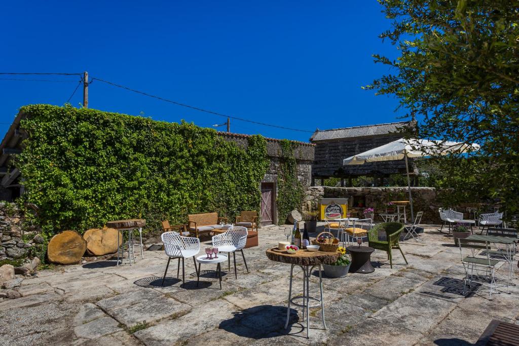 a patio with chairs and tables and a hedge at Casa Lela Dumbria in Dumbría