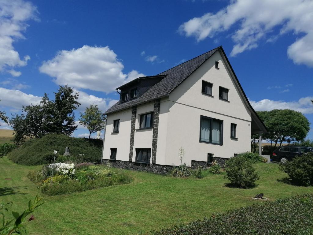 uma casa branca com um telhado preto numa colina em Ferienwohnung "Haus am Weifberg" Hinterhermsdorf em Sebnitz