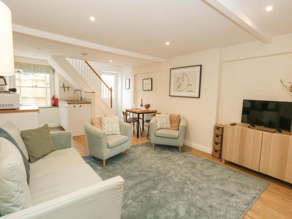 a living room with a white couch and a tv at Bobbin Cottage in Swanage