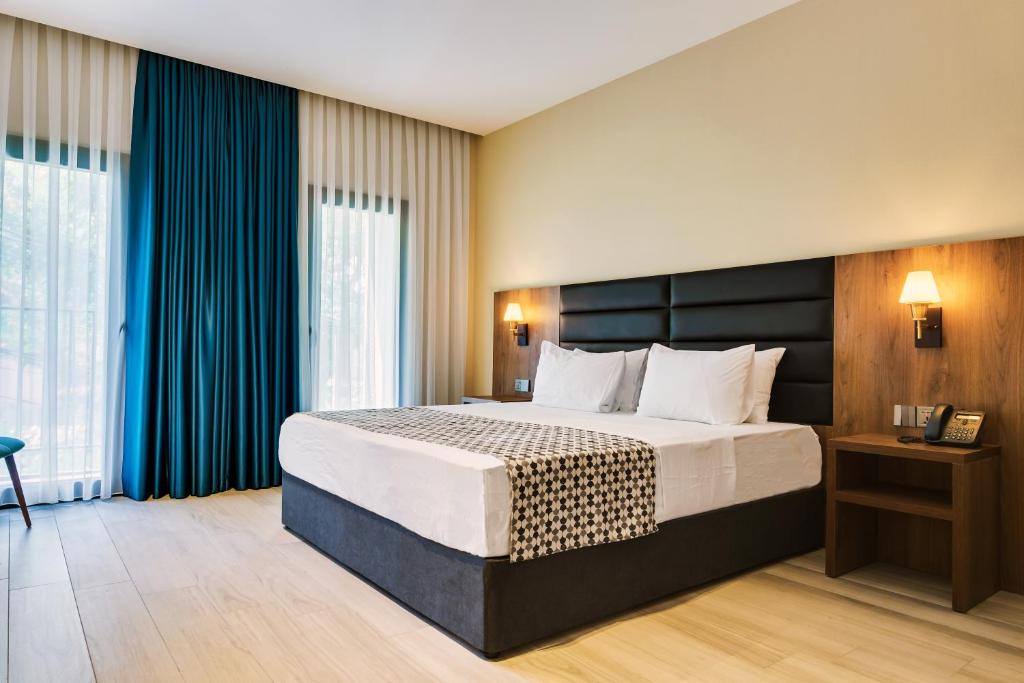 a bedroom with a large bed with blue curtains at Eleven Inn Tbilisi in Tbilisi City
