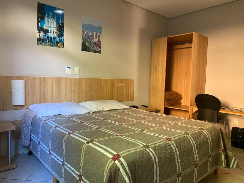 sypialnia z łóżkiem z zieloną kołdrą w obiekcie CHA Mime Hotel w mieście Blumenau