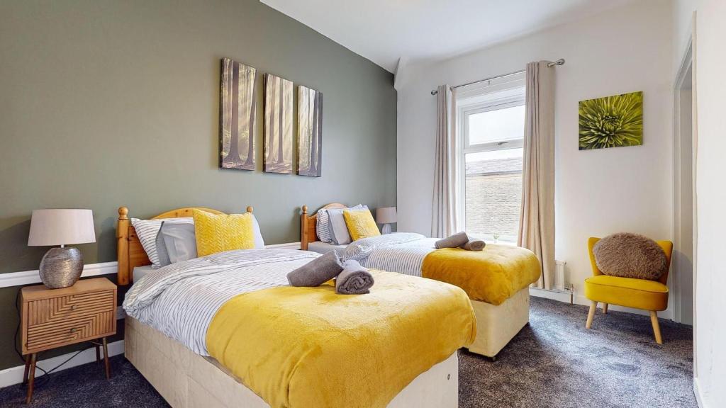 um quarto com 2 camas e uma janela em Modernised 3-bedroom Blackburn townhouse sleeps 6 em Rishton