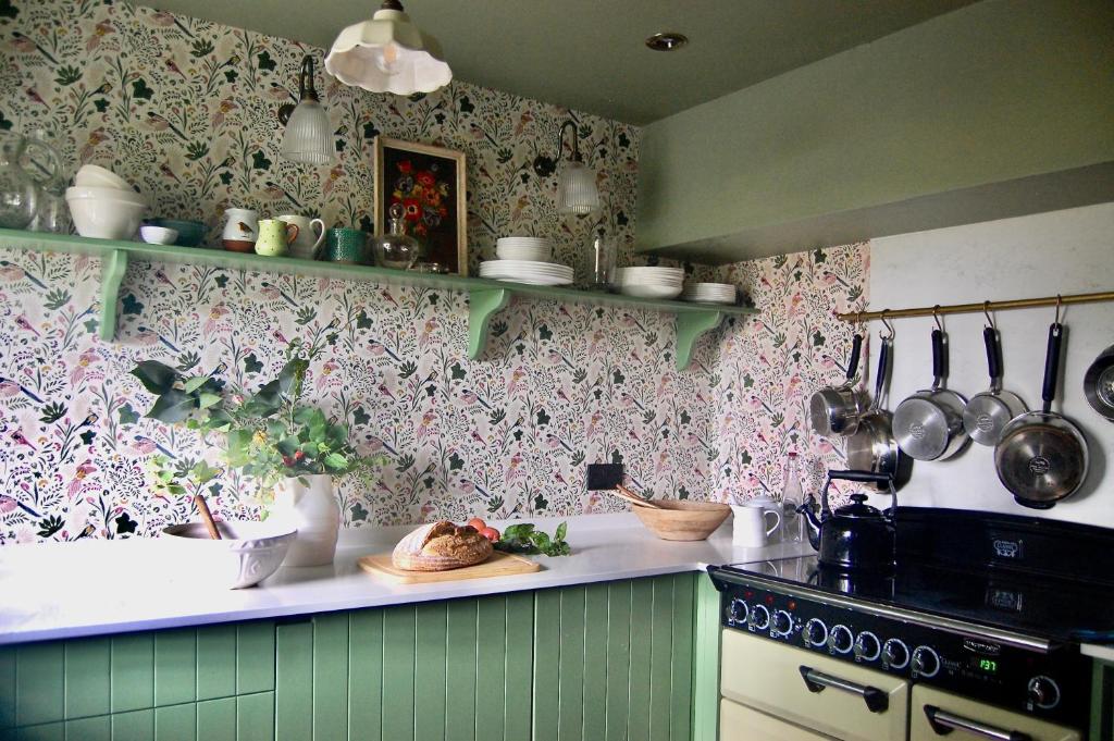 a kitchen with green and pink wallpaper and a stove at Little Cottage Shipton in Shipton under Wychwood