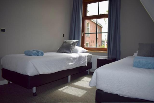 a bedroom with two beds and a window at Hotel Restaurant 't Ronde Loegh in Winschoten