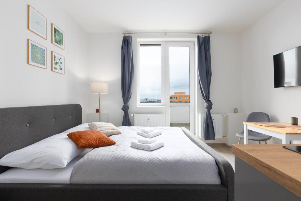 a bedroom with a bed with white sheets and a window at Apartmán u metra s terasou in Prague