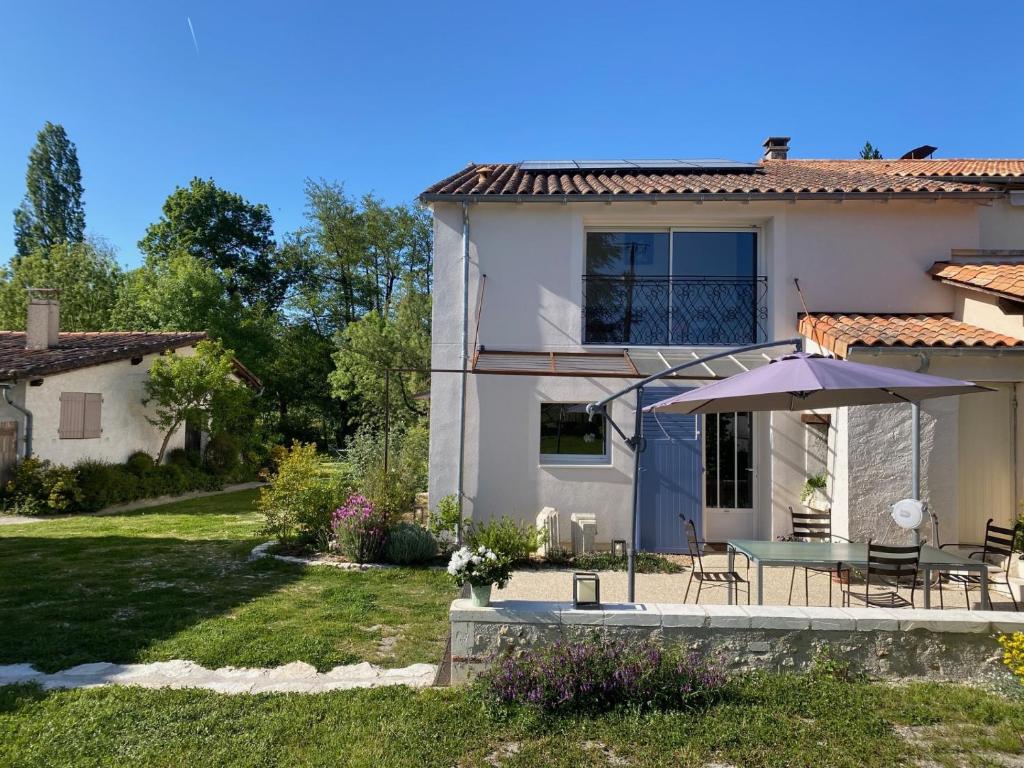 a house with a patio and a table with an umbrella at Maison d hôtes Les Chantours dans réserve naturelle 15 hectares in Saint-Antoine-Cumond