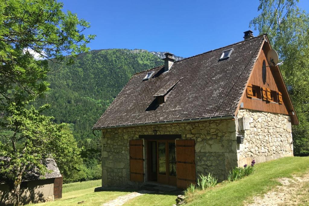 an old stone house on a hill with mountains in the background at Maison bucolique en Chartreuse in Chenevey