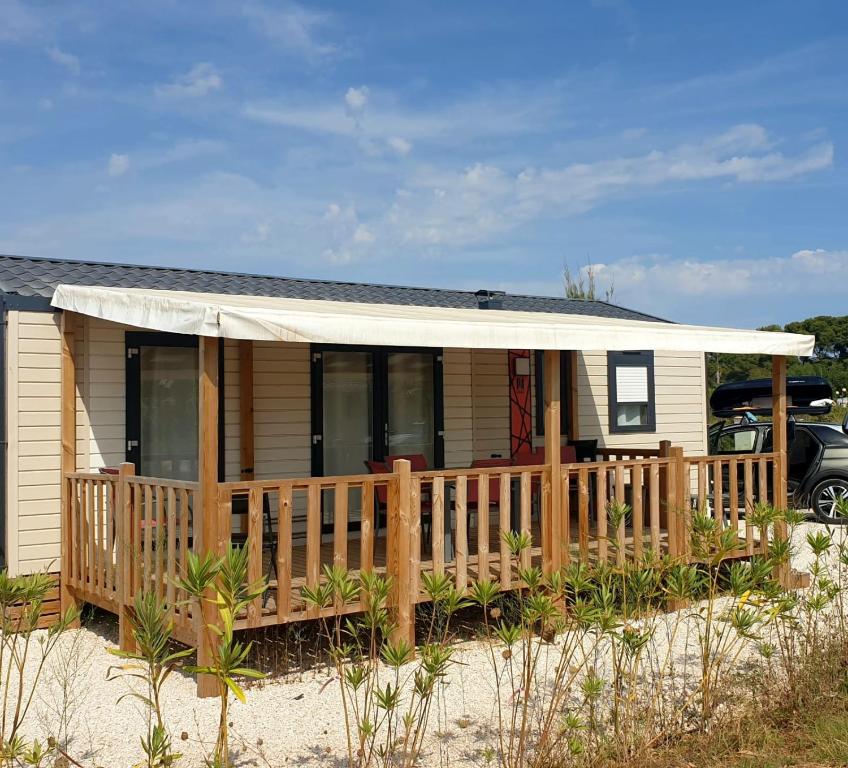 une petite maison avec une terrasse couverte et une terrasse dans l'établissement Camping Les Pins maritimes, à Hyères