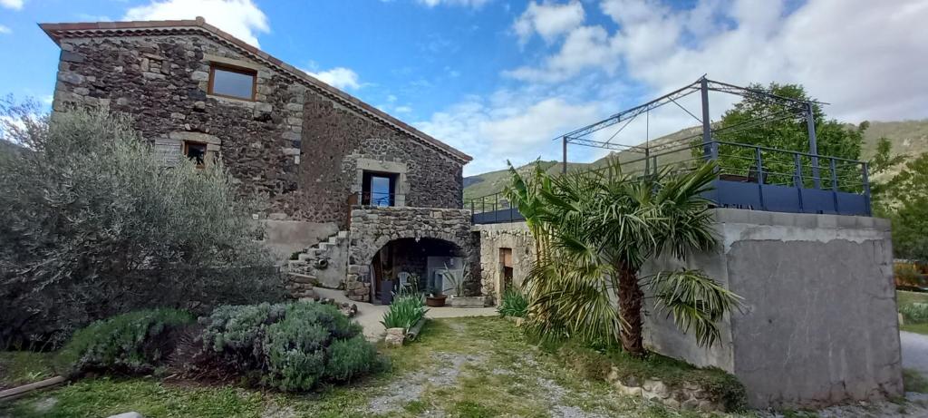 een stenen huis met een trap aan de zijkant bij Le gîte des Oliviers in Meyras