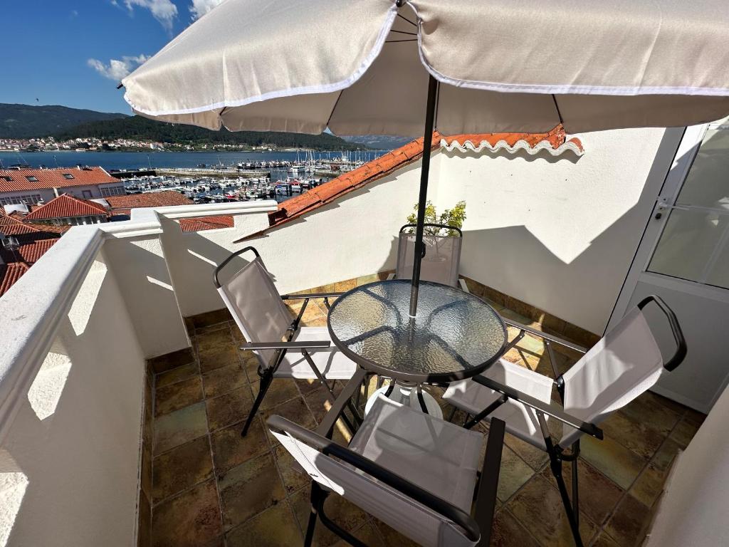a table and chairs on a balcony with an umbrella at Gran ático dúplex centro Muros,Terraza con vistas in Muros