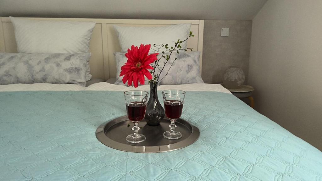 a tray with two glasses and a red flower on a bed at auszeit34 in Ebelsbach