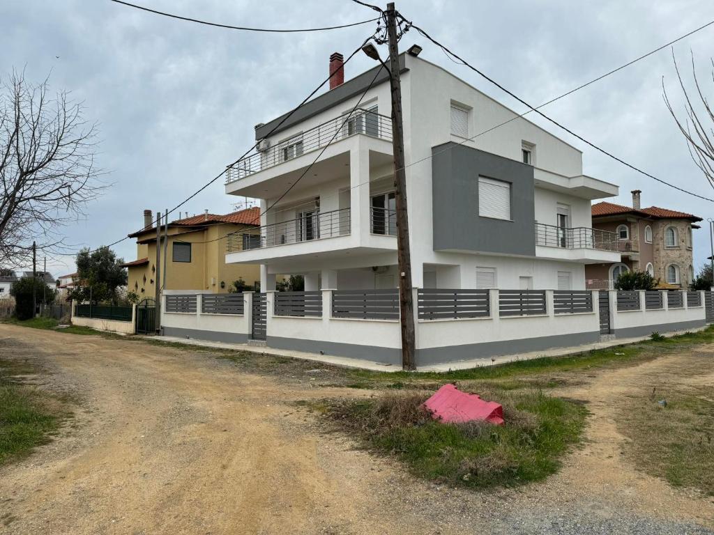 a large white building on the side of a dirt road at Adoniss Apartmentss in Paralia Dionysiou