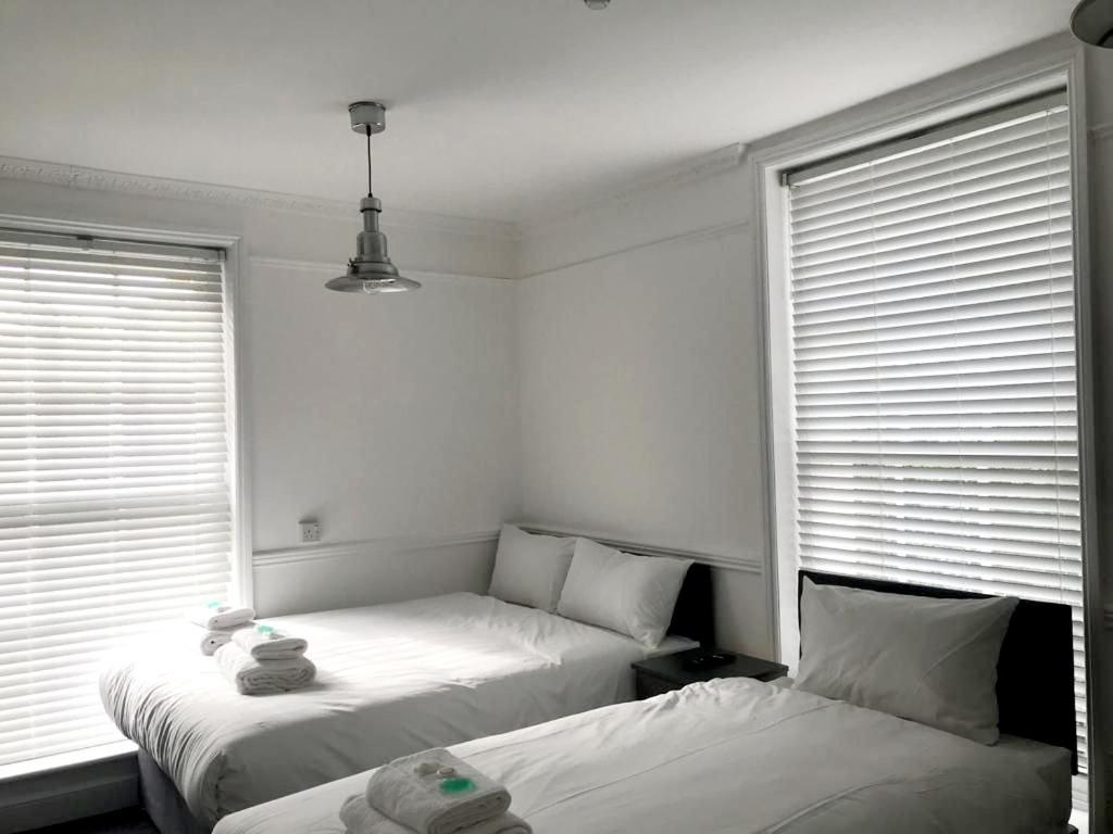 two beds in a room with two windows at Nysdill Hotel Norwich in Norwich