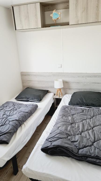 two beds sitting next to each other in a room at Mobilhome Domaine des pins à Marennes plage in Marennes