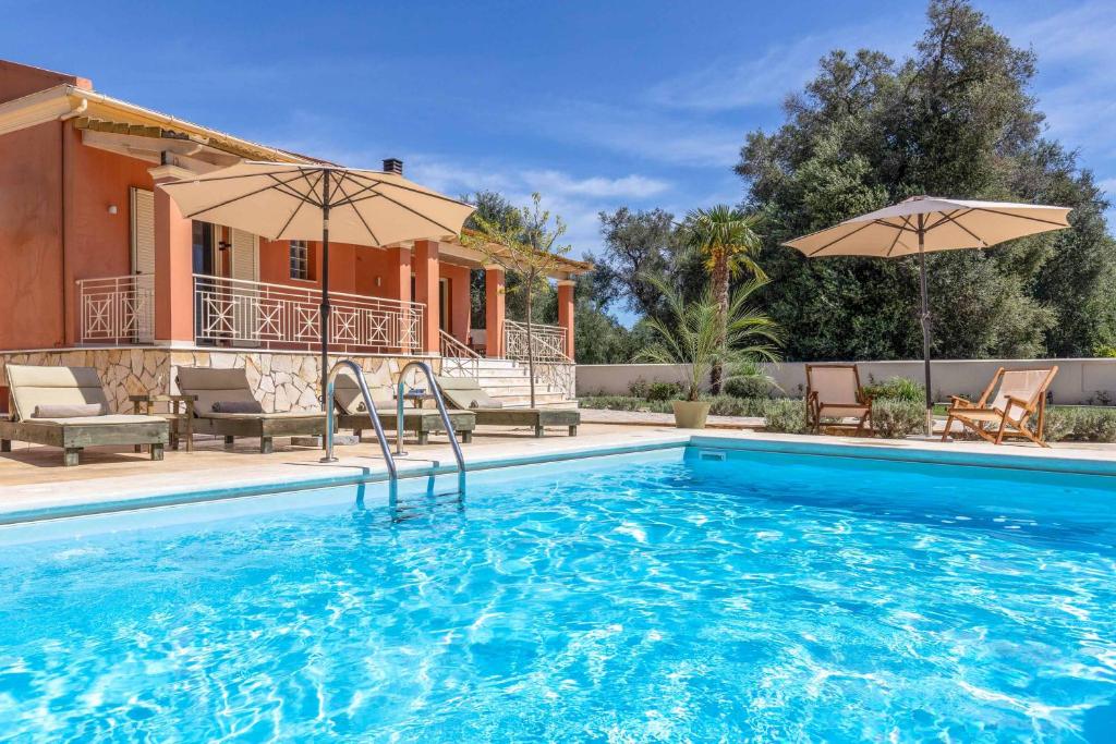 a swimming pool in front of a house at Villa Loukiana in Kavos