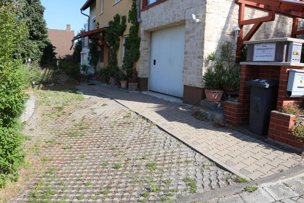 a brick sidewalk next to a house with a white garage at Kleine Wohngelegenheit in Chemnitz