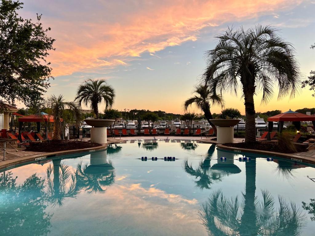 a large swimming pool with palm trees and a sunset at Marina Inn at Grande Dunes in Myrtle Beach