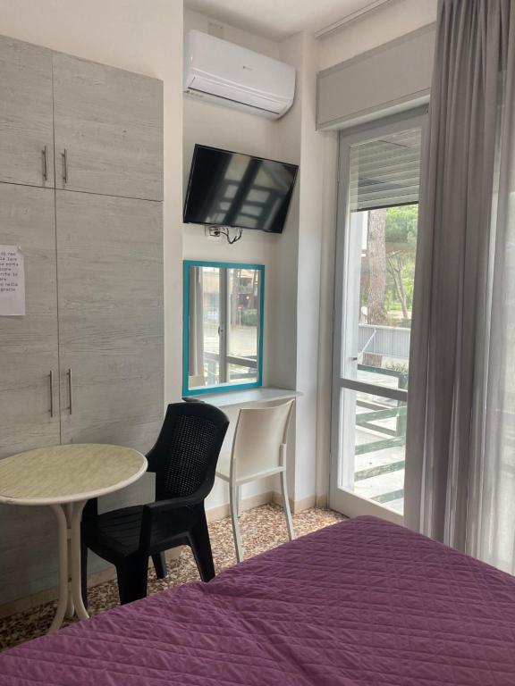 um quarto com uma cama, uma mesa e uma janela em MDP Hotel em Cervia