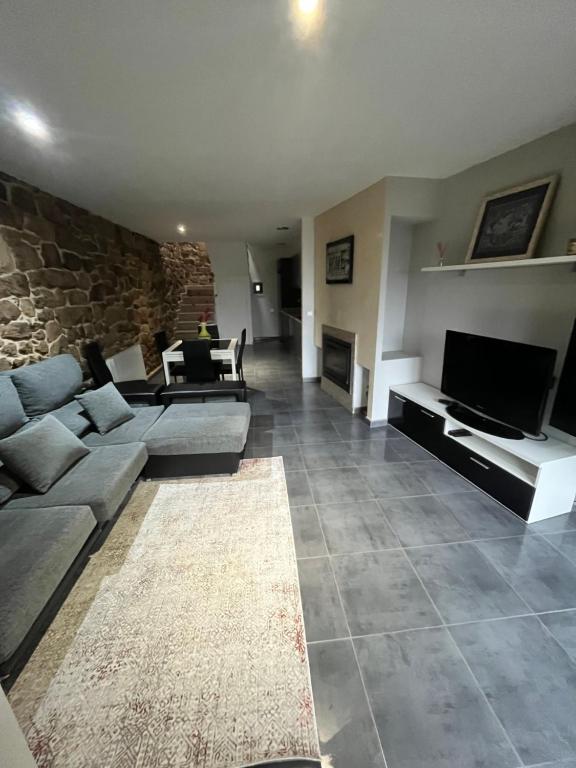 una sala de estar con sofás y una pared de piedra. en A MIÑA CASIÑA -TERMAS OURENSE, en Ourense