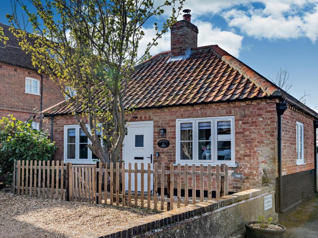 a small red brick house with a wooden fence at 1 Bed in Beccles 94297 in Geldeston