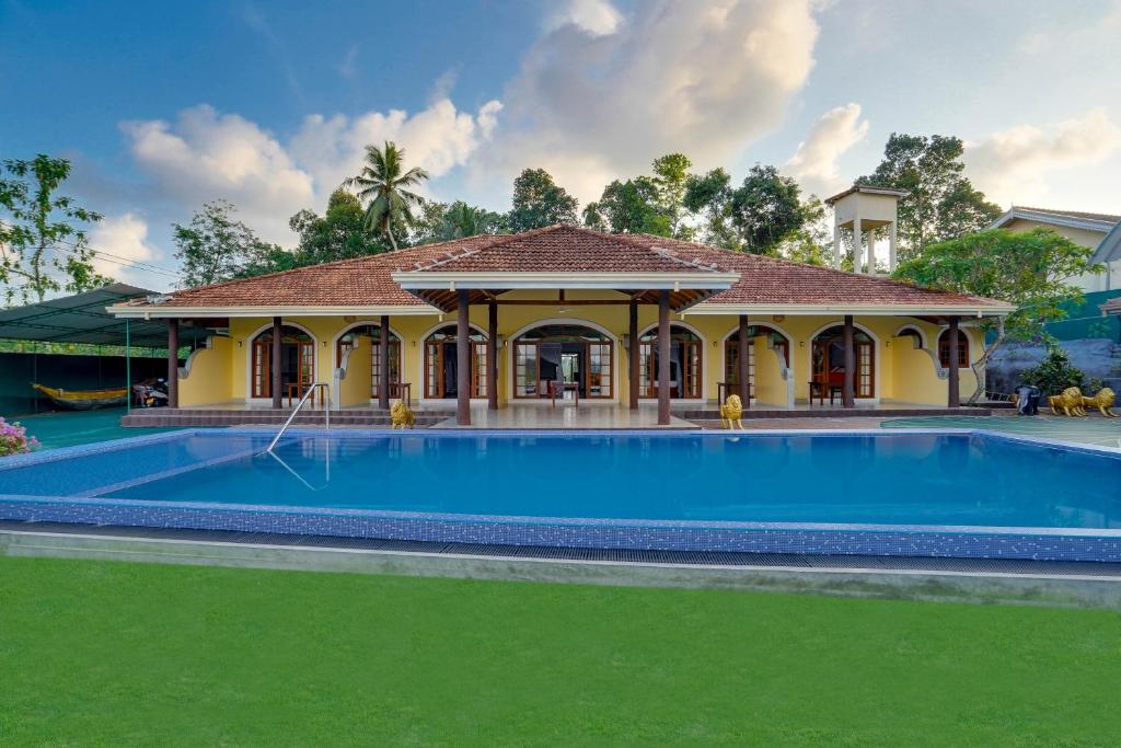 a swimming pool in front of a house at Treetop Resort By Scenery Villas in Dharga Town