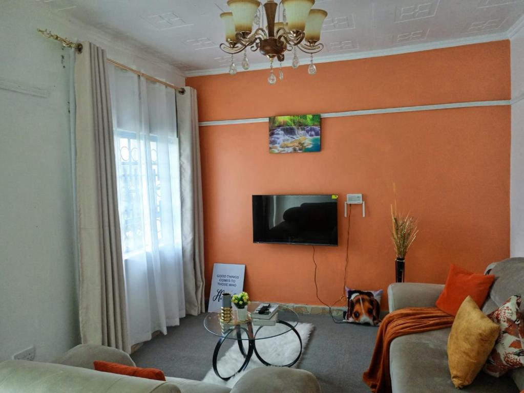 ein Wohnzimmer mit einem Sofa und einem TV an der Wand in der Unterkunft Kai Suite Kitale in Kitale