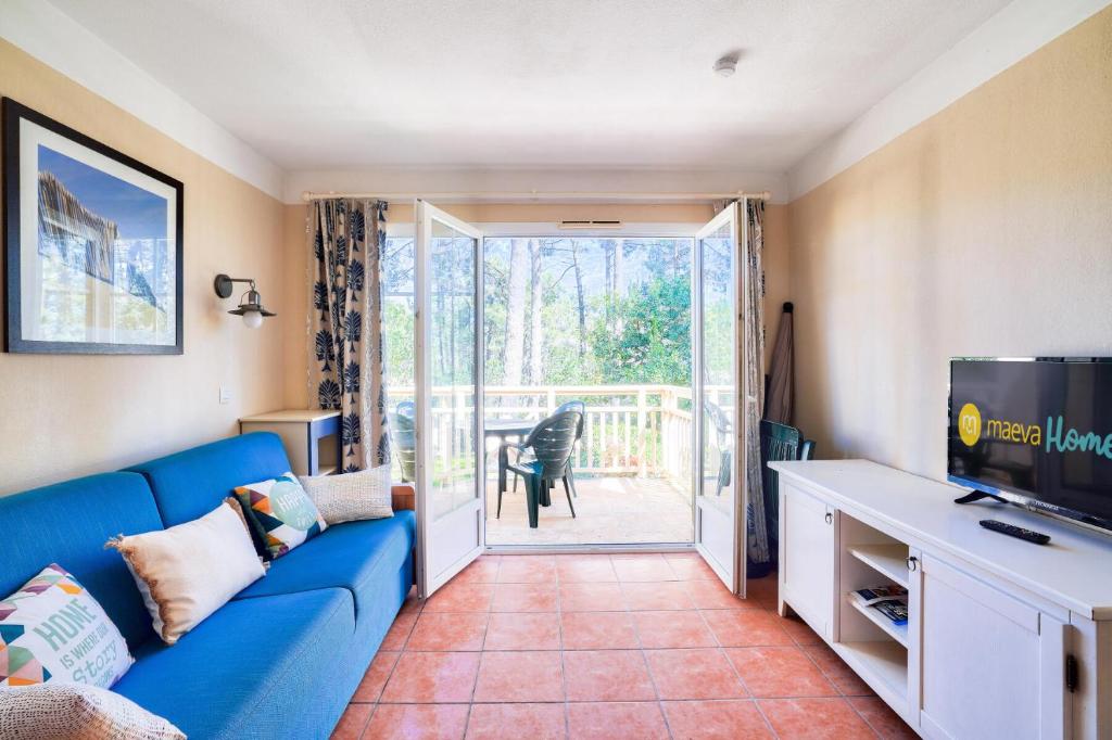 un salon avec un canapé bleu et une télévision dans l'établissement Résidence Lacanau Les Pins - maeva Home - Appartement 2 pièces 4 personnes - Sélection MAE-5031, à Lacanau